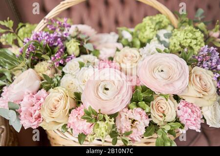 Blumen Lieferung. Blumenarrangement im großen Korbkorb. Wunderschöner Blumenstrauß aus gemischten Blumen in der Hand der Frau. Blumengeschäft Konzept . Schön frisch Stockfoto