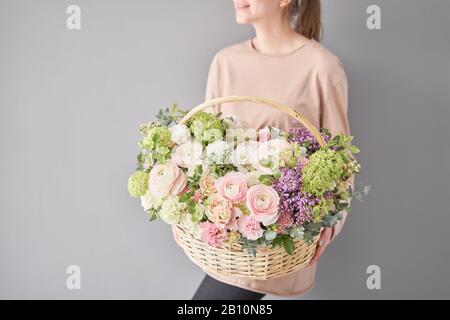 Blumen Lieferung. Blumenarrangement im großen Korbkorb. Wunderschöner Blumenstrauß aus gemischten Blumen in der Hand der Frau. Blumengeschäft Konzept . Schön frisch Stockfoto