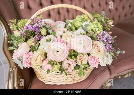 Blumen Lieferung. Blumenarrangement im großen Korbkorb. Wunderschöner Blumenstrauß aus gemischten Blumen in der Hand der Frau. Blumengeschäft Konzept . Schön frisch Stockfoto