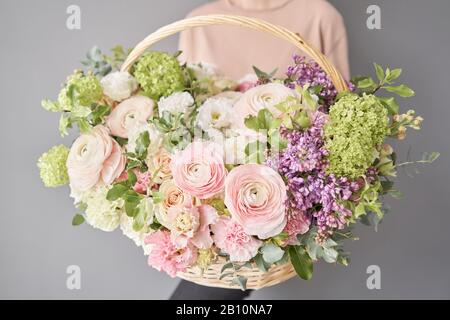 Blumen Lieferung. Blumenarrangement im großen Korbkorb. Wunderschöner Blumenstrauß aus gemischten Blumen in der Hand der Frau. Blumengeschäft Konzept . Schön frisch Stockfoto