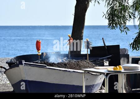 Typische Küche der andalusischen Küste: Sardinen und Garnelen, die bei einem Kohlefrasen in einem Boot braten Stockfoto