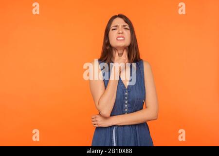 Ungesunde brünette Frau im Kleid, die den Hals berührt und Schmerzen schmerzt, Halsschmerzen erleidet, Atemwegsinfektion mit Kehlkopfentzündung, Grippe. IND Stockfoto