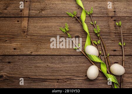 Easter Konzept ohne Verschwendung. Federtwische mit frischen grünen Blättern, Holzeiern, Punktband aus Polka. Alte Vintage Holzbretter Hintergrund, Kopierraum, Oberteil Stockfoto