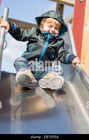 Kleiner Junge mit Kapuze auf Rutsche Stockfoto