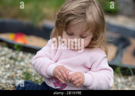 Kleines Mädchen spielt mit Blumen im Garten Stockfoto