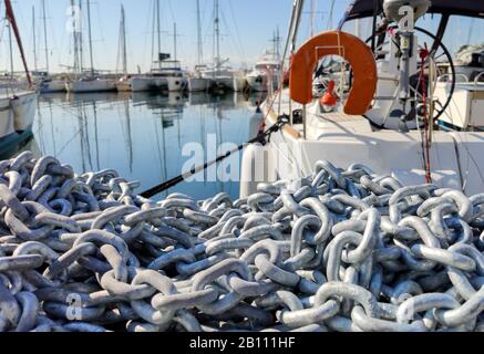 Ankerkette Pile Nahansicht, Schwere Industriekette auf dem Hafendeck, verwackelte Kreuzfahrtschachten in einem Yachthafen Hintergrund Stockfoto