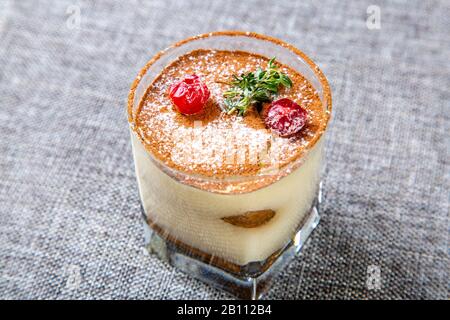 Panna Cotta Dessert aus transparentem Glas, verziert mit Kirschen und Minze. Stockfoto