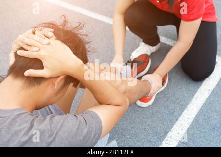 Nahaufnahme des jungen asiatischen Paares, das auf der blauen Laufstrecke im Stadion Sit-ups macht Stockfoto