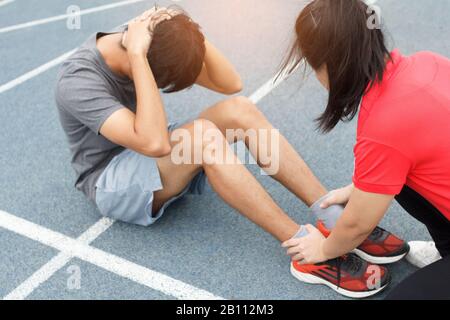 Nahaufnahme des jungen asiatischen Paares, das auf der blauen Laufstrecke im Stadion Sit-ups macht Stockfoto