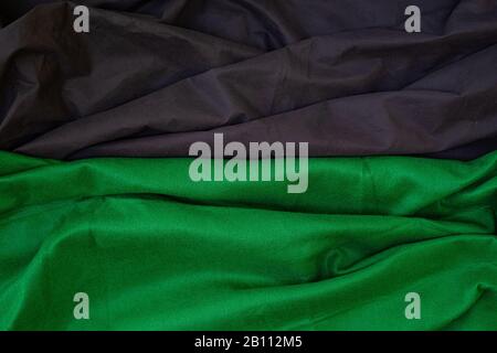 Stoffwellen schließen den Hintergrund, Gestapeltes, Knitterförmiges Material 3-farbig schwarz-grün-weiß, elegantes Tapeten-Design, gewellte Falten von grunger Seidentextur saßen Stockfoto