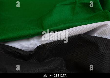 Stoffwellen schließen den Hintergrund, Gestapeltes, Knitterförmiges Material 3-farbig schwarz-grün-weiß, elegantes Tapeten-Design, gewellte Falten von grunger Seidentextur saßen Stockfoto