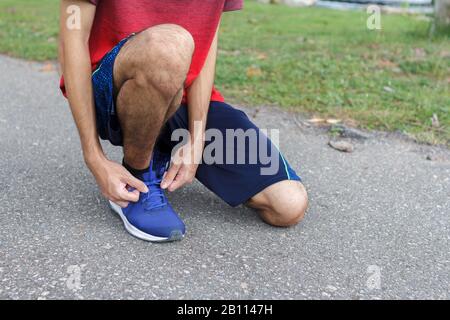 Nahaufnahme des Sportlers. Vor dem Üben bindet er Turnschuhe an Laufschuhe. Laufkonzept Trainingskonzept. Stockfoto