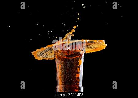 Bier spritzt in Glas auf schwarzem Hintergrund Stockfoto