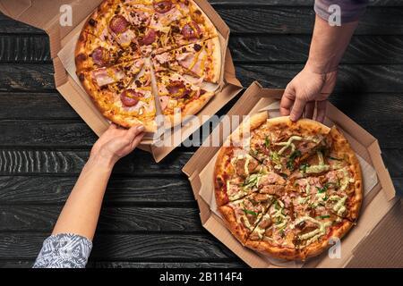 Overhead-Ansicht der Hände, die Pizza aus dem Karton nehmen Stockfoto