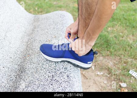 Nahaufnahme des Sportlers. Vor dem Üben bindet er Turnschuhe an Laufschuhe. Laufkonzept Trainingskonzept. Stockfoto