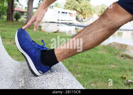 Junger Sport man Läufer, der sich vor dem laufen die Beine streckt - Trainingskonzept Stockfoto