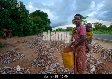 Frau mit Baby sammelt Steinen, Mosambik, Afrika Stockfoto