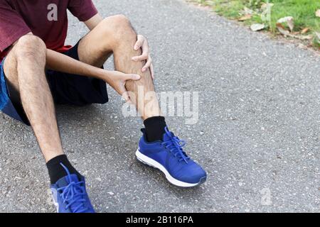 Nahaufnahme des Sportmannes, der nach dem laufen mit Schmerzen bei sportlicher Knieverletzung leidet.Verletzung durch Trainingskonzept. Stockfoto