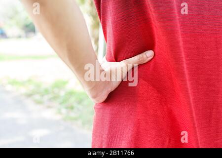 Junge Mann-Läuferin, die nach dem laufen an Rückenschmerzen oder Wunde Taille leidet - Trainingskonzept, .Verletzung durch Trainingskonzept. Stockfoto