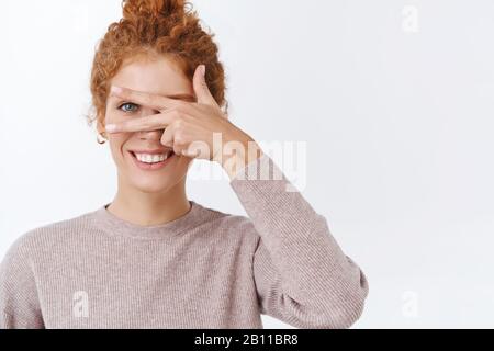 Glücks-, Wohlfühl- und Lifestyle-Konzept. Wunderschöne, feminine, hübsche Rotkopffrau mit lockigen Haaren, gekämmt in Bun, mit stilvoller Bluse, die Ruhe zeigt Stockfoto