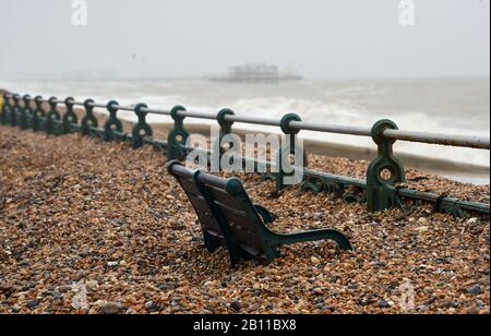 Hove UK 22. Februar 2020 - Die Bänke an der Küste von Hove sind fast vollständig von Schindel bedeckt, der durch die jüngsten Stürme aufgeworfen wurde. Das stürmische Wetter wird sich in den nächsten Tagen in ganz Großbritannien fortsetzen und es wird mit weiteren Überschwemmungen und Schäden gerechnet: Credit Simon Dack / Alamy Live News Stockfoto