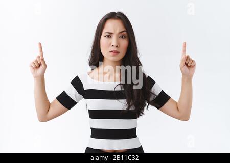 Porträt einer skeptischen, unsicheren Brünette ostasiatischer Frau in gestreiftem T-Shirt, aufschäumen und eine Augenbraue anheben, mit Unglauben schlittern, zeigen Stockfoto