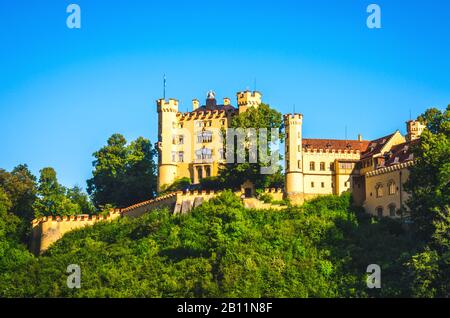 Schloss Hohenschwangau steht bei Sonnenaufgang auf Hochland. Stockfoto