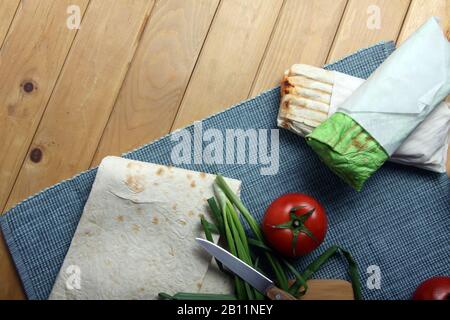 Zwei Doner-Kebabs und Zutaten Lavasch und Tomate auf Holzhintergrund flach gelegt. Bild enthält Kopierbereich Stockfoto