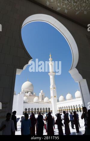 Brillantes Minarett aus weißem Marmor und Kuppeln, die von einem Torbogen in der Scheich Zayed Grand Moschee, Abu Dhabi, eingerahmt werden Stockfoto