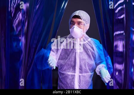 Asiatischer Mann, der Schutzkleidung und Schutzmaske trägt und im chemischen Labor arbeitet Stockfoto