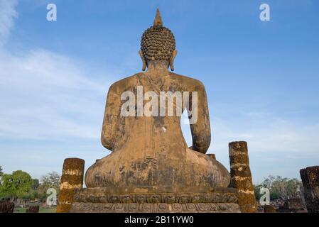 Blick von der Rückseite der antiken Skulptur eines sitzenden Buddha gegen den blauen Himmel. Sukhothai, Thailand Stockfoto