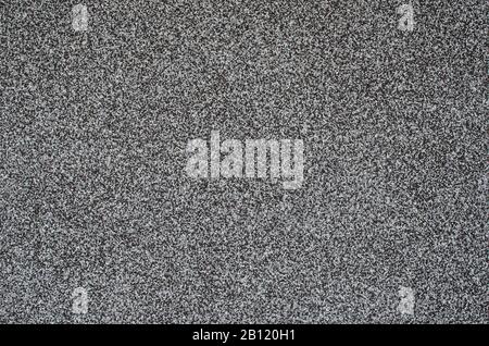 Grauer Hintergrund, Wand mit schwarzen, weißen und grauen Körnern. Abstrakter Hintergrund in Schwarzweiß. Struktur aus grauem Granit. Wandhintergrund, Muster Stockfoto