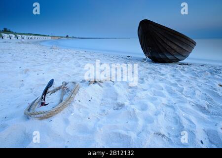 Einsames kleines Holzboot liegt nach Sonnenuntergang vor Anker am Strand, Weststrand, Darß, Ostsee, Mecklenburg-Vorpommern, Deutschland Stockfoto