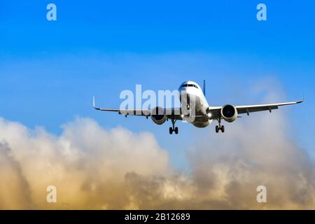 Passagierjet kommt an Land an einem Flughafen gegen blauen Himmel und bunte Wolken Stockfoto