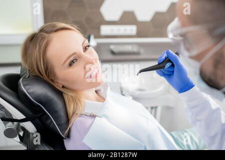 Hübsche junge blonde Frau mit dem Kopf auf schwarzem Lederpolster Stockfoto