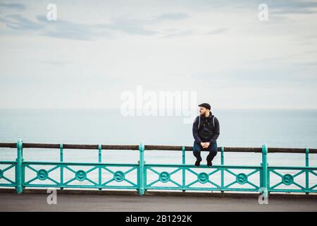 Tourist liegt an einem Geländer an der Küste, Brighton Beach, Brighton, England, Stock Photo Tourist, an einem Geländer an der Küste, Brighton Beach, Brighton, England Stockfoto