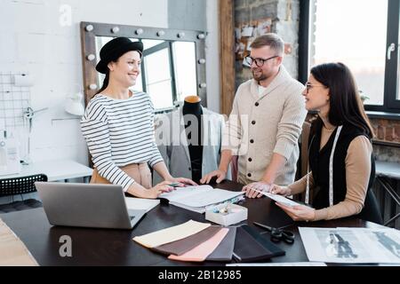 Drei glückliche Designer diskutieren über neue Models für die saisonale Kollektion Stockfoto