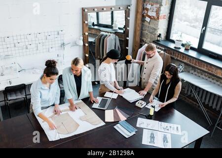 Zwei Gruppen professioneller Modedesigner, die mit Skizzen und Mustern arbeiten Stockfoto