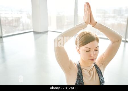 Hübsches Mädchen mit geschlossenen Augen, das ihre Hände über den Kopf zusammenhält Stockfoto