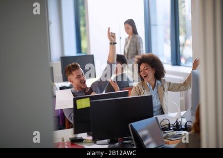 Glückliche Kollegen mit den Händen in der Luft, nachdem sie gute Geschäftsnachrichten erhalten haben: Positiv, glücklich, Gefühle, Erfolgskonzept Stockfoto