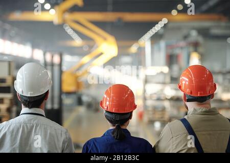 Rückansicht des Teams zeitgenössischer Ingenieure in Hardhats Stockfoto