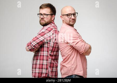 Zwei Freunde hatten einen Sturz, sie stehen mit gekreuzten Armen zurück und schauten auf die Kamera. Stockfoto