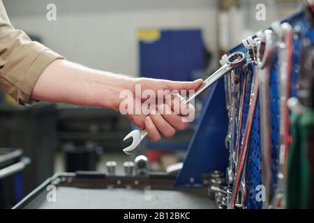 Hand des jungen Technikers, Mechanikers oder Reparaturwerkers, der eines der Schlüssel nimmt Stockfoto