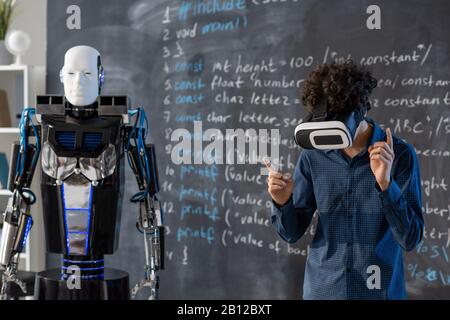 Student im vr-Headset, das über einen Automatisierungsroboter über virtuelle Steuerung arbeitet Stockfoto
