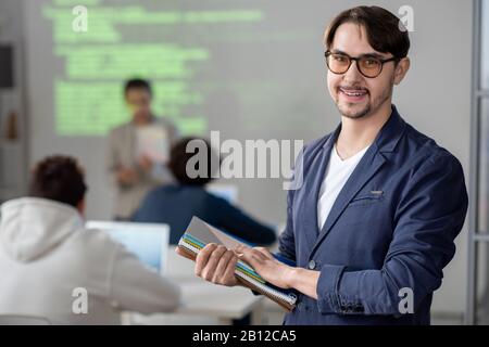 Junger Lehrer vor dem Hintergrund seiner Teilnehmer an der Konferenz Stockfoto