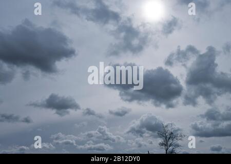 wolkenverhangener Himmel mit Sonne hinter den Schichten höherer Wolken Stockfoto