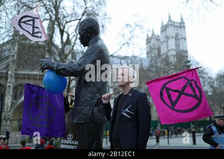 Ein Protestler neben der Statue von Nelson Mandela auf dem Parliament Square, London, während eines Extinction Rebellion (XR) märz. Stockfoto