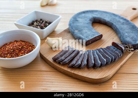 Schneiden Sie Scheiben der speziellen Pirot-Hufeisenwurst - Peglana Pirotska kobasica, aus Kalbfleisch, Schaf- und Ziegenfleisch, mit Zusatz von Knoblauch Stockfoto