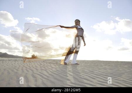 Frau, die ein rotes transparentes Tuch in der Brise hält, Dunes, Corralejo, Fuerteventura, Kanarische Inseln, Spanien, Europa Stockfoto