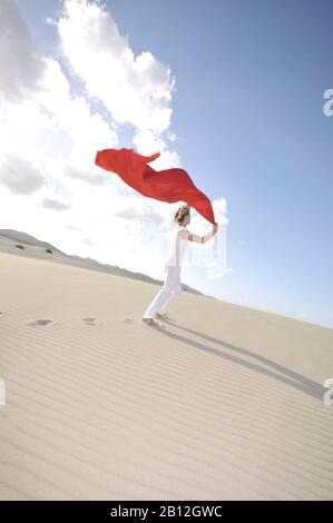 Frau, die ein rotes transparentes Tuch in der Brise hält, Dunes, Corralejo, Fuerteventura, Kanarische Inseln, Spanien, Europa Stockfoto